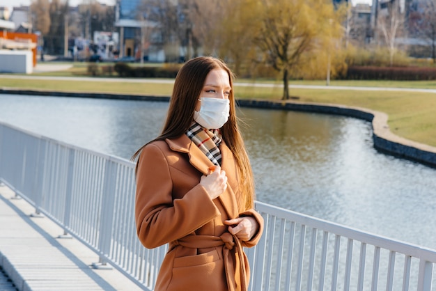 Una ragazza cammina in una maschera durante la pandemia e il coronovirus. Quarantena.