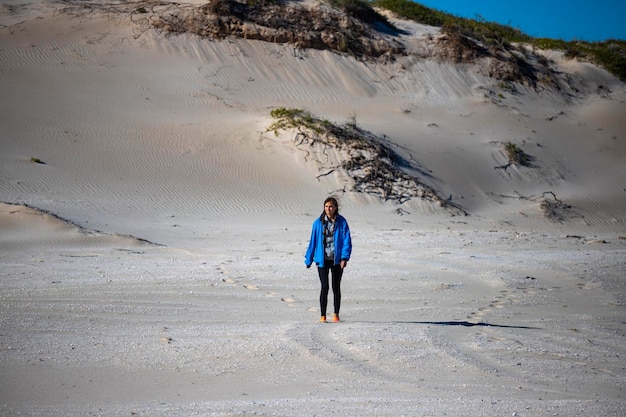 una ragazza cammina lungo la cima di un'enorme duna di sabbia nella baia di corallo nell'Australia occidentale a piedi