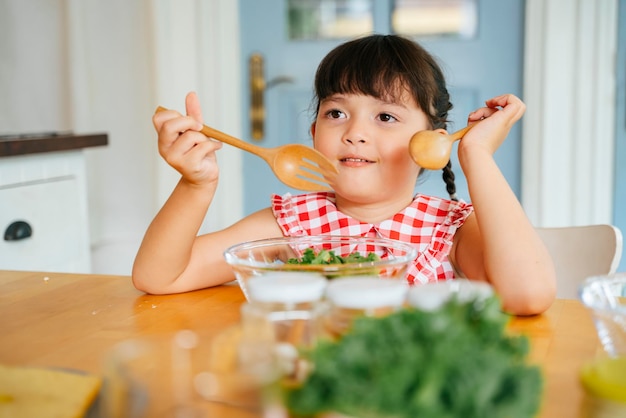 Una ragazza carina che mangia l'insalata a casa