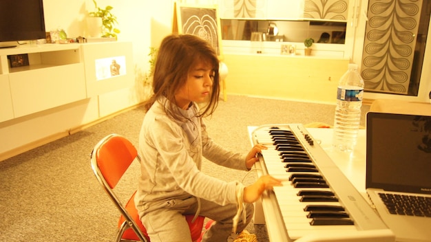 Una ragazza carina che suona il pianoforte in una casa illuminata