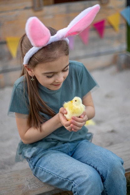 Una ragazza carina con le orecchie da coniglio tiene in mano un pollo Buona Pasqua