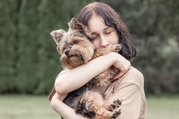 Una ragazza carina con uno Yorkshire terrier per strada Abbracci con il tuo cagnolino nel parco