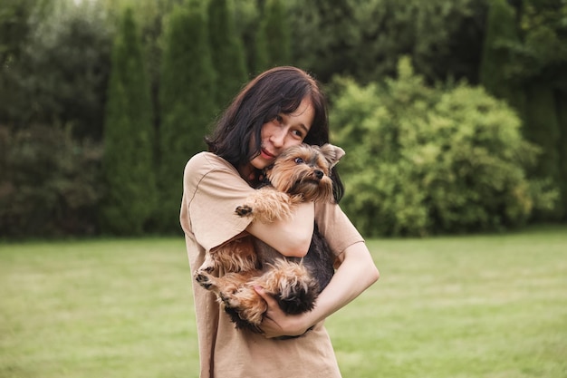 Una ragazza carina con uno Yorkshire terrier per strada Abbraccia con il tuo cagnolino nel parco