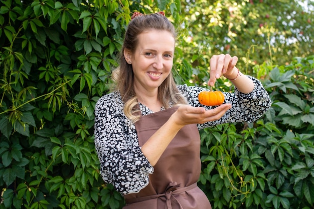 Una ragazza carina contadina tiene in mano una piccola zucca