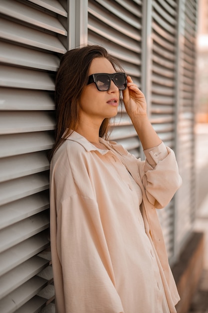 Una ragazza carina in beige e in posa di occhiali da sole