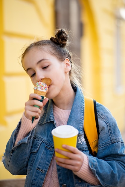 Una ragazza carina mangia il gelato e beve il tè fuori Takeaway Felicità Infanzia