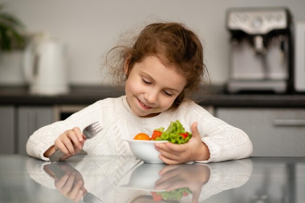 Una ragazza carina mangia un'insalata di verdure fresche Cibo sano Infanzia