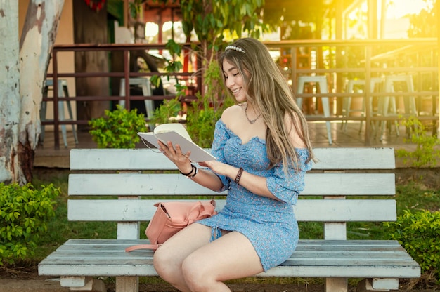 Una ragazza carina seduta su una panchina a leggere un libro ragazza latina piuttosto giovane che legge un libro su una panchina