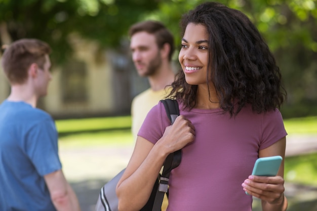 Una ragazza carina sorridente con uno smartphone in mano