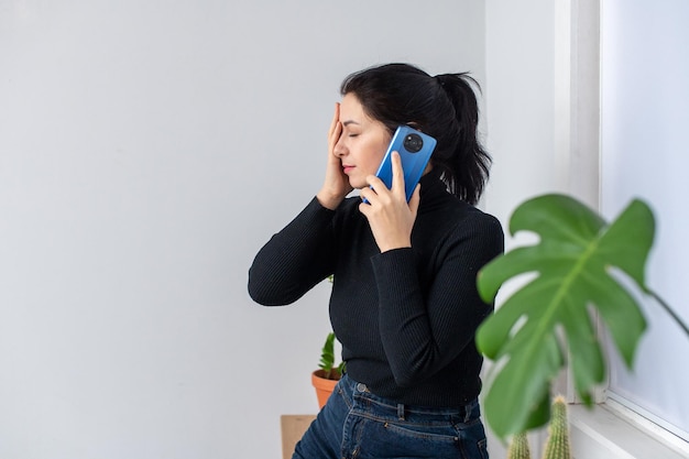 Una ragazza carina sta parlando al telefono e si tiene la testa con la mano Ricevendo cattive notizie