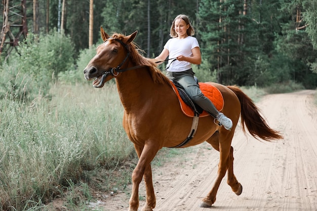 Una ragazza cavalca un cavallo nella calda estate nella foresta