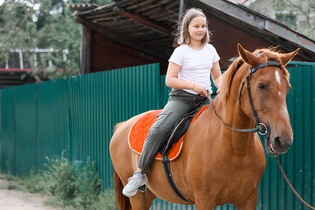 Una ragazza cavalca un cavallo nella calda estate