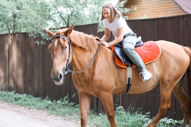 Una ragazza cavalca un cavallo nella calda estate