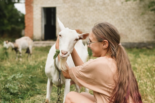 Una ragazza che abbraccia la sua capra bianca come un'amica del villaggio