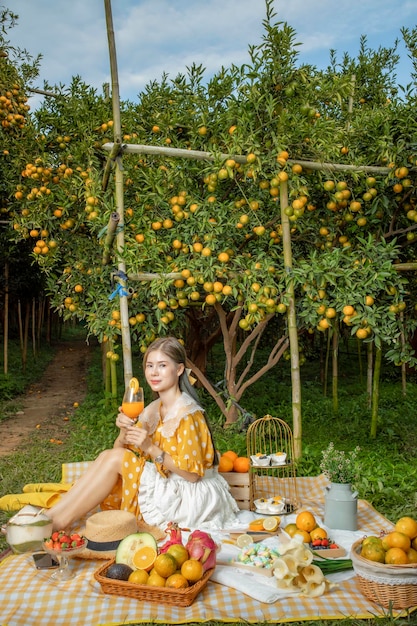 Una ragazza che fa un picnic in una piantagione di arance