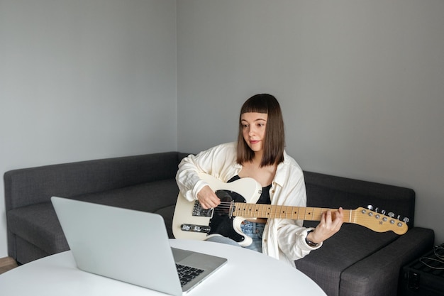 Una ragazza che impara a suonare la chitarra a casa.