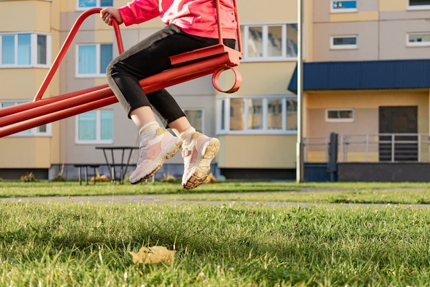 Una ragazza che oscilla su un'altalena in un parco giochi nel cortile di un condominio Attività all'aperto