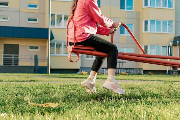 Una ragazza che oscilla su un'altalena in un parco giochi nel cortile di un condominio Attività all'aperto