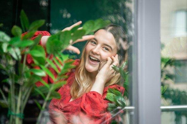 Una ragazza che parla al telefono vista dalla strada attraverso la finestra