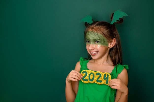 Una ragazza che ride con un viso truccato a forma di drago mostra i numeri del nuovo anno 2024