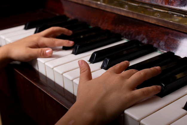 Una ragazza che ritaglia la tastiera del pianoforte da vicino