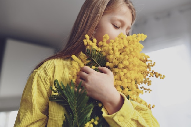 Una ragazza che sente l'odore della mimosa gialla in primavera