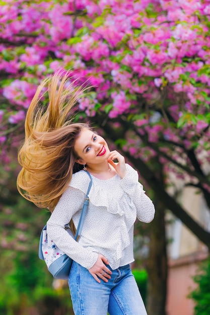 Una ragazza che si diverte in vacanza sullo sfondo del fiore di ciliegio rosa