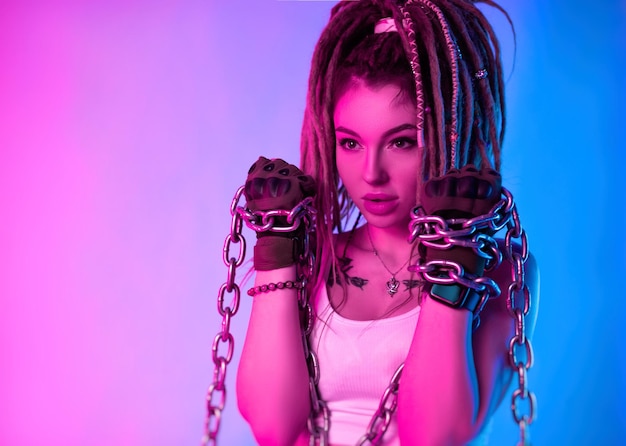 Una ragazza combattente con catene sulle mani con bellissimi dreadlock in testa alla luce al neon