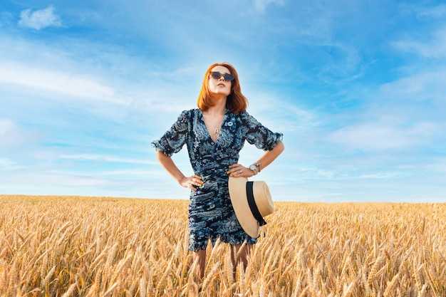 Una ragazza con bei capelli in piedi nel mezzo di un campo di grano. Capelli naturali sani