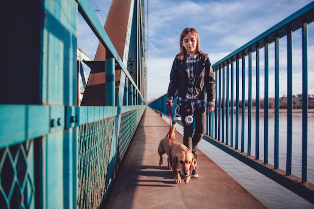 Una ragazza con cane che cammina attraverso il ponte