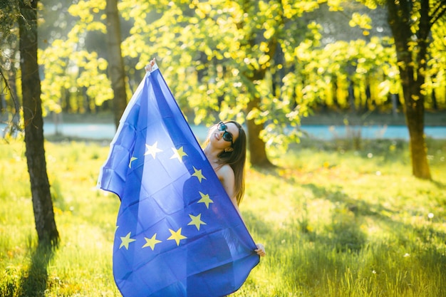 una ragazza con i capelli castani in posa con la bandiera dell'unione europea