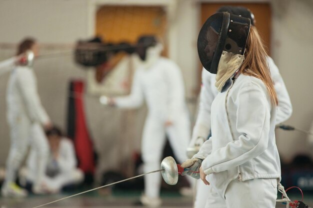 Una ragazza con i capelli lunghi che ha duello di scherma in un torneo