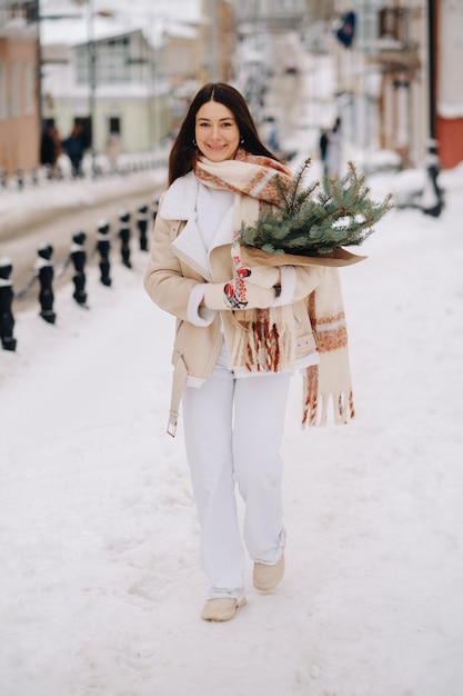 Una ragazza con i capelli lunghi in inverno per strada con un mazzo di rami di abete fresco