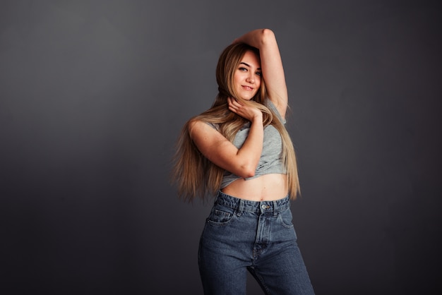 Una ragazza con i capelli lunghi sembra allungata su uno sfondo grigio senza ritocco.