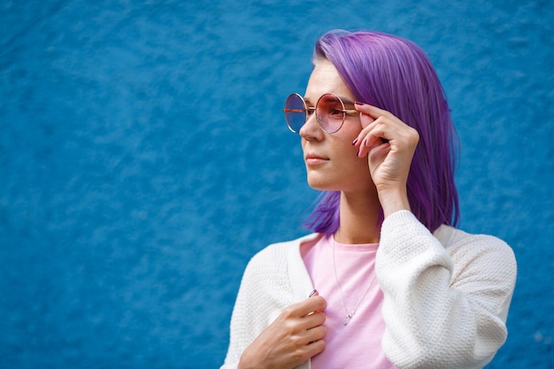 Una ragazza con i capelli viola in occhiali rosa