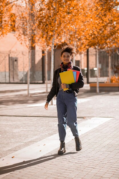 Una ragazza con i libri in mano che cammina per strada