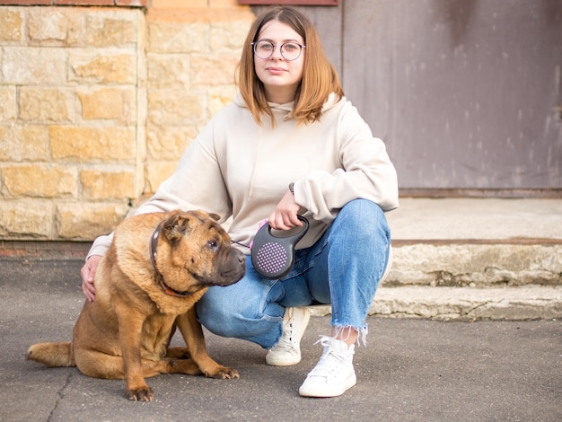 Una ragazza con il suo vecchio sharpei sullo sfondo del paesaggio urbano