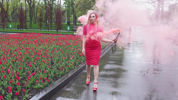 Una ragazza con il trucco con le trecce arcobaleno in abito rosso in posa in abito rosso