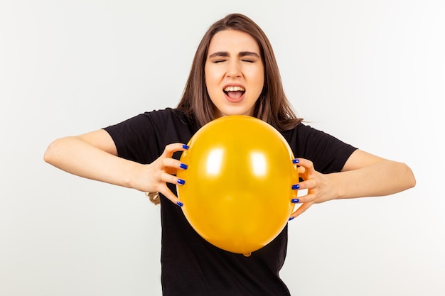 Una ragazza con in mano un palloncino arancione e urlando