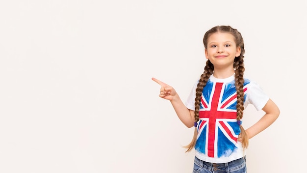 Una ragazza con la bandiera della Gran Bretagna indica il tuo annuncio su uno sfondo bianco e isolato