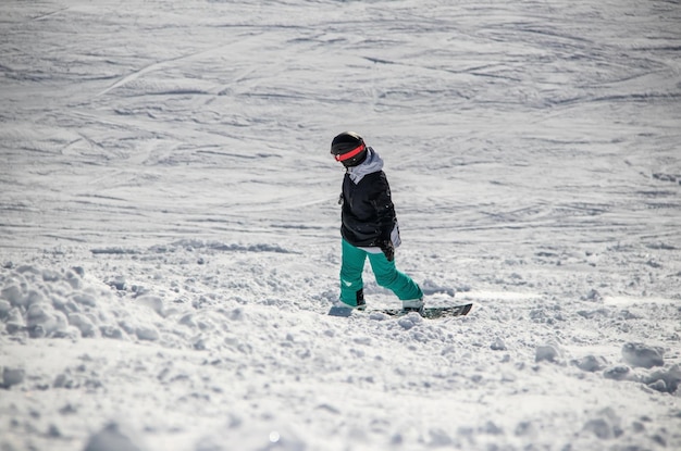 Una ragazza con lo snowboard scende lungo il fianco della montagna