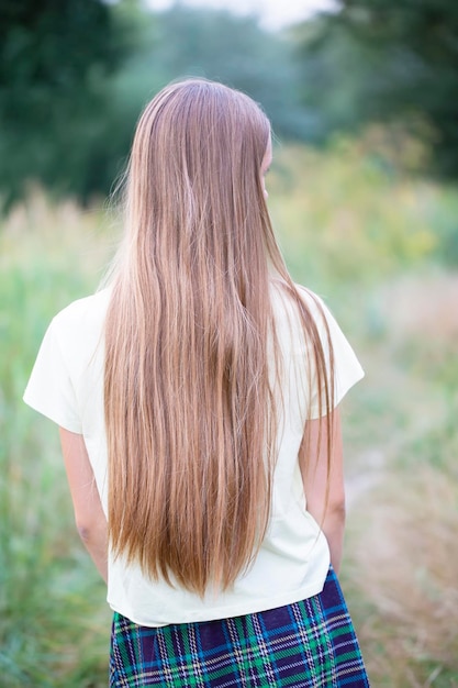 Una ragazza con lunghi capelli bianchi da dietro sullo sfondo di un prato verde