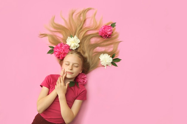 Una ragazza con peonie, bei capelli biondi e una colorata manicure per bambini