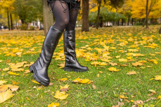 Una ragazza con stivali caldi posa su uno sfondo di foglie cadute