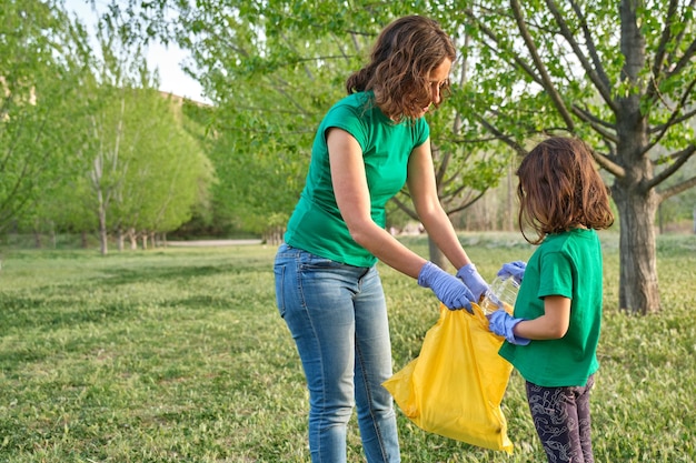 Una ragazza con sua madre che raccoglie plastica dal campo per prendersi cura della natura