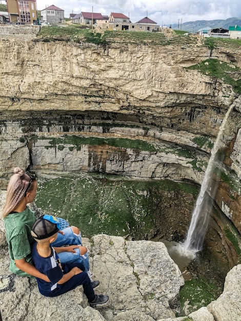 Una ragazza con un bambino sullo sfondo della cascata Tobot cascate Khunzakh Daghestan Russia 2021