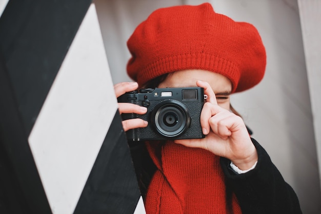 Una ragazza con un berretto rosso scatta foto in una strada cittadina. Foto di alta qualità