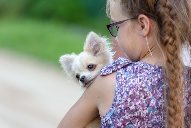 Una ragazza con un cagnolino sulla spalla vista posteriore