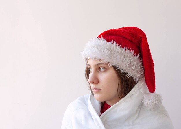 Una ragazza con un cappello da Babbo Natale avvolto in un primo piano del viso di una coperta bianca