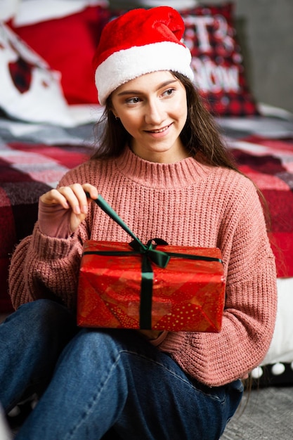 Una ragazza con un cappello da Babbo Natale con doni sullo sfondo degli interni di Capodanno.